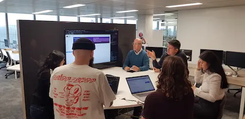 Group of 5 colleagues chatting around a screen